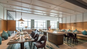 A modern dining area with multiple tables and chairs, large windows, and a central island. - Juntels Panan Jinhua (Jinhua)