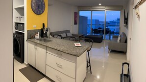 Una cocina moderna con lavadora integrada, cafetera y un reloj grande en la pared.