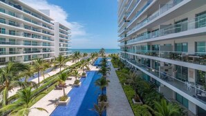 Un hotel moderno con una piscina larga, palmeras y vista al océano.