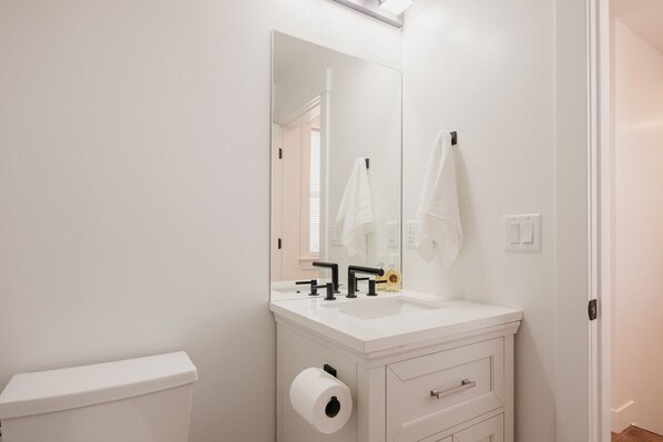 Un bagno bianco con lavandino, specchio e water.