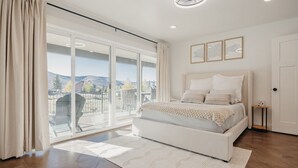 A bedroom with a large bed, a sliding glass door to a balcony, and a view of the outdoors. - Lakeview Lodge - Lakeside Escape (Scofield)