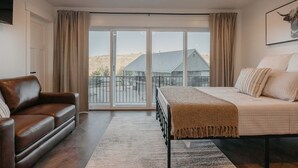 A bedroom with a bed, a sofa, and a large window with curtains. - Mountain View Lodge - Spacious Cabin Retreat with Hot Tub, (Scofield)