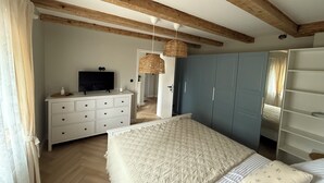 A bedroom with a bed, a dresser, a television, and a wardrobe.