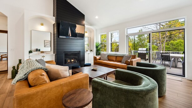 A modern living room with a fireplace, leather sofas, a coffee table, and a view of the outdoors. - Thoughtfully Designed Luxury Group Retreat (Ephraim)