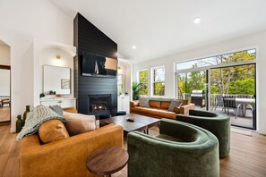 Una sala de estar moderna con chimenea, sofás de cuero, una mesa de centro y vistas al exterior.