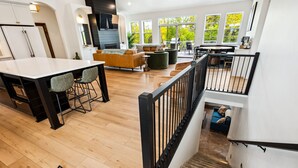 A spacious kitchen with a large island, a dining area with a sofa and chairs, and a staircase leading to an upper level. - Thoughtfully Designed Luxury Group Retreat (Ephraim)