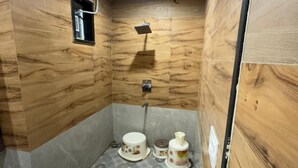A small bathroom with a wooden wall, a shower, and a patterned floor. - KANHA RETREAT - VRINDAVAN (Vrindavan)