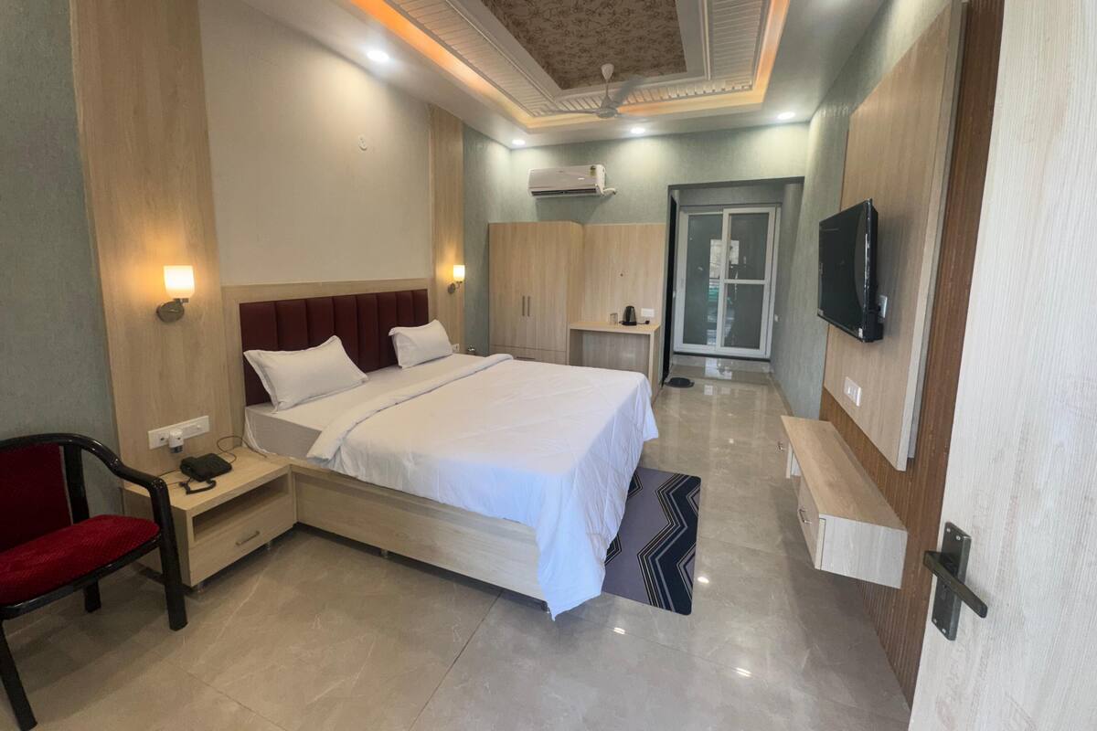 Habitación de hotel con una cama grande, mesitas de noche, una silla, un televisor y un armario.