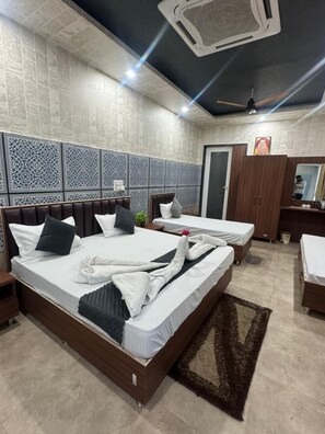 A hotel room with two beds, a wardrobe, a mirror, and a ceiling fan.