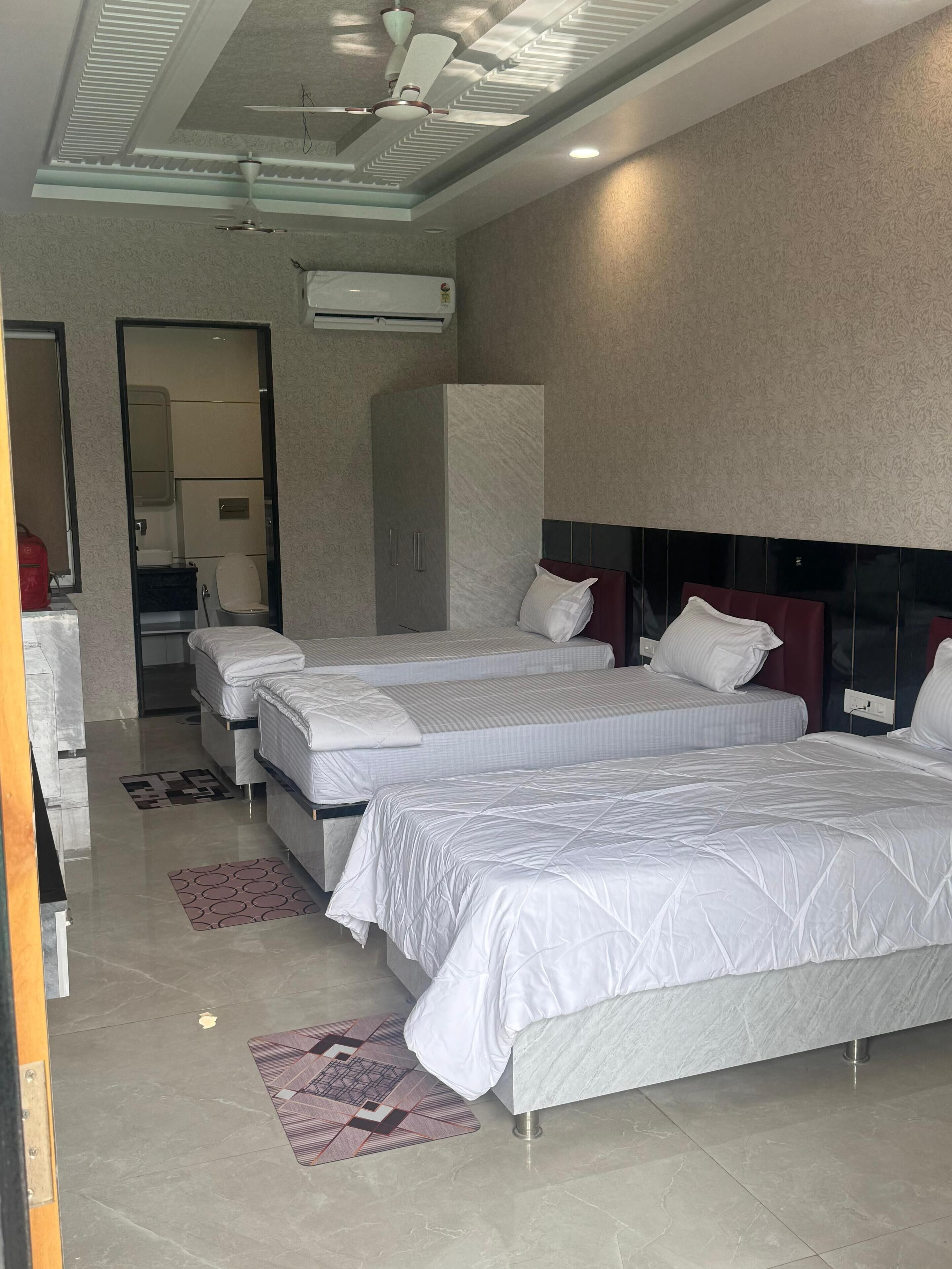 A modern hotel room with two beds, a wardrobe, a mirror, and a ceiling fan.