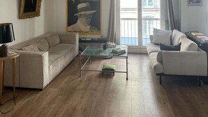 A living room with two sofas, a coffee table, and a poster on the wall. - Balcony Apartment on Canal Saint Martin (Paris)