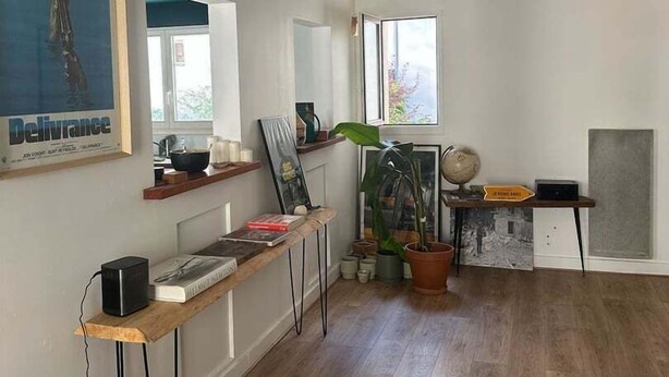 A spacious room with hardwood flooring, a desk with a globe and a sign, a large window, and a framed picture on the wall. - Balcony Apartment on Canal Saint Martin (Paris)