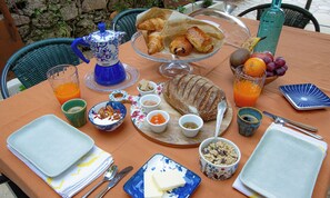 A table set with breakfast items including croissants, bread, fruit, and beverages. - Moulin Lombard B&B (Les Arcs-sur-Argens)