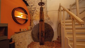 A rustic interior with a stone wall, a wooden spiral staircase, and a round mirror with a candle. - Moulin Lombard B&B (Les Arcs-sur-Argens)