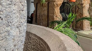 A stone archway with hanging plants and a stone bench. - Moulin Lombard B&B (Les Arcs-sur-Argens)