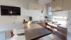 A modern kitchen with a flat-screen TV, a coffee maker, and a sink. - Mobile Home in Bodensdorf by Lake Ossiach (Steindorf am Ossiacher See)