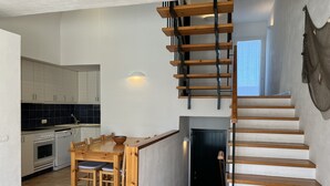 A modern kitchen with white cabinets, a dining table, and a staircase with wooden steps. - Large house with shared pool near the sea (Fornells)