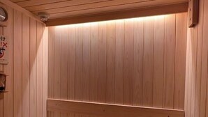 Een houten sauna met een bank en een kleine tafel.