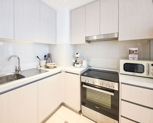 A modern kitchen with stainless steel appliances, a microwave, and a built-in oven. - Modern 1BR Apartment near Yas Mall & Ferrari World (Abu Dhabi)