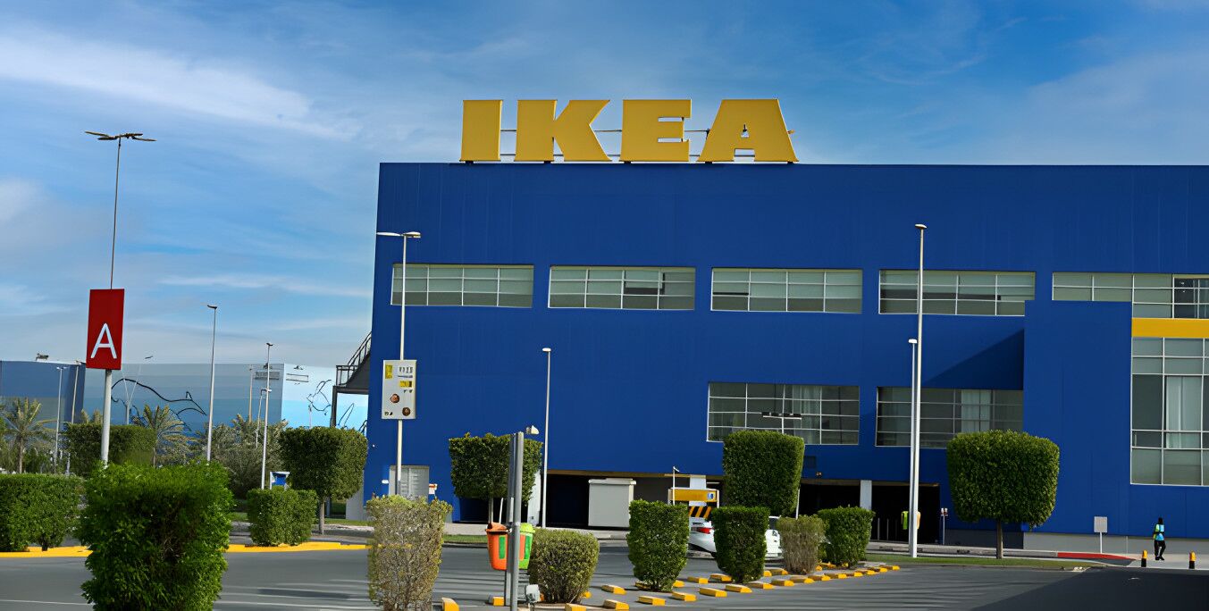 A blue building with the IKEA logo, surrounded by greenery and a parking lot.
