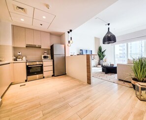 Eine moderne Küche mit Einbauofen, Mikrowelle und Kühlschrank, Holzboden und einem Essbereich mit Sofa und Pflanzen.