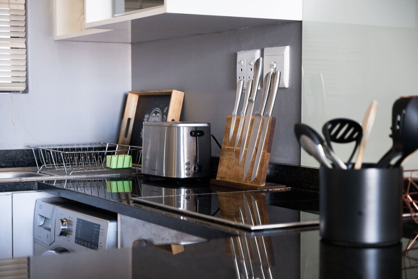 Une cuisine moderne équipée d’une cuisinière en acier inoxydable, d’un grille-pain et d’un bloc à couteaux.