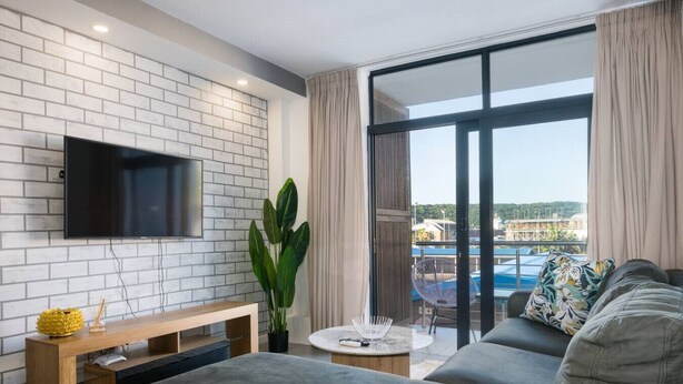 Een moderne woonkamer met een flatscreen televisie, een ruime bank, een salontafel en een kamerplant.