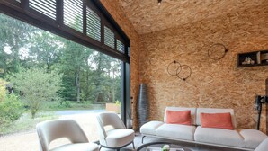 A modern living room with a large window, a white sofa, two armchairs, and a coffee table. - Design house with wellness in nature (Biron)