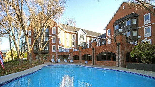 A swimming pool surrounded by brick buildings with multiple windows and balconies.