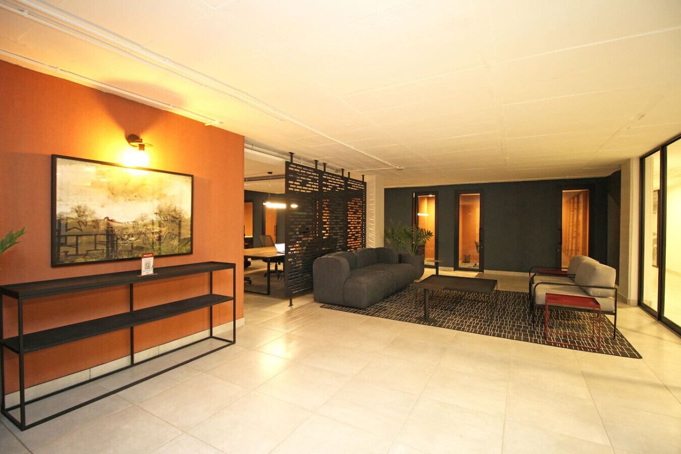 En moderne hotellobby med en sofa, et sofabord og et spiseområde i baggrunden.