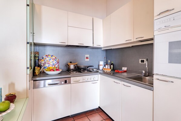 A compact kitchen with white cabinets, a built-in dishwasher, and a stove. - Hanbury Apt Pool And Sea (Ventimiglia)