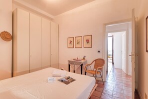 Ein Hotelzimmer mit Bett, einem kleinen Tisch mit Stuhl, einem Kleiderschrank und einer Tür zu einem anderen Raum.