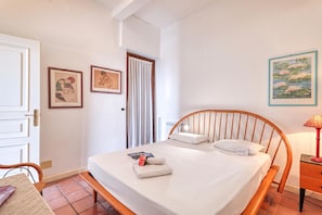 A bedroom with a wooden bed, a nightstand, a lamp, and two framed artworks on the wall. - Hanbury Apt Pool And Sea (Ventimiglia)