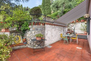 Un patio con un muro de piedra, plantas en macetas, una mesa y sillas.