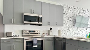 A modern kitchen with grey cabinets, a stainless steel microwave, an oven, and a dishwasher.
