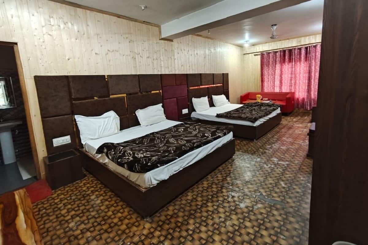 A hotel room with two beds, a red sofa, and a patterned floor.