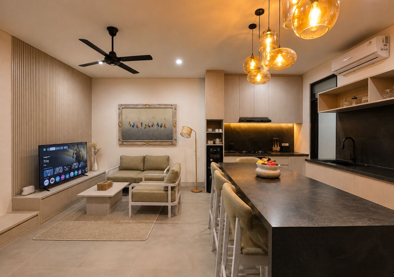 A modern living room with a flat-screen TV, sofa, coffee table, and a dining area with bar stools.