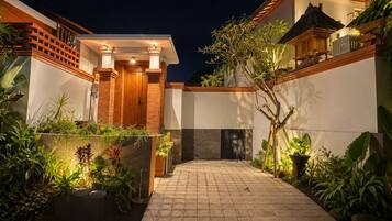 Uma casa moderna com calçada pavimentada, porta de madeira e entrada bem iluminada.