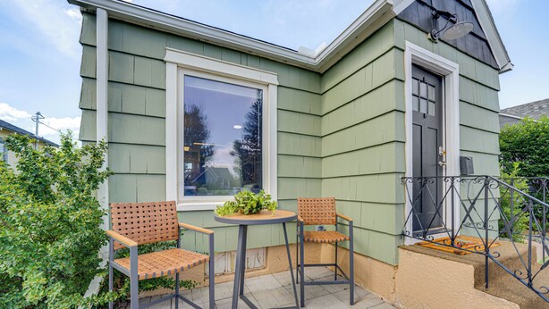 A green house with a large window, two chairs, and a small table. - 2 Mi to Dtwn: Family Home in Cheyenne! (Cheyenne)