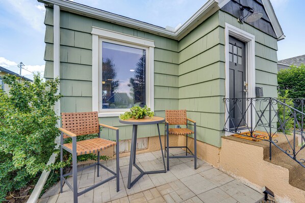 A small patio with two chairs and a table, a window, and a door.