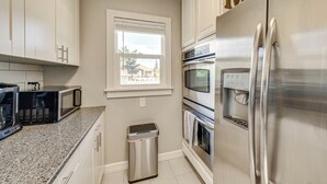 A kitchen with white cabinets, a stainless steel refrigerator, a microwave, an oven, and a trash can. - 2 Mi to Dtwn: Family Home in Cheyenne! (Cheyenne)