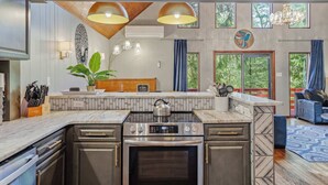 A kitchen with a built-in oven, a stove, and a countertop with a kettle.