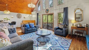 A spacious living room with a large round coffee table, two sofas, and a dining area with a wooden table and chairs.