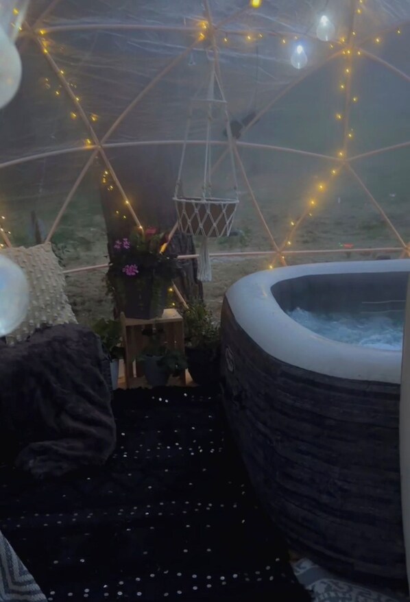 A cozy interior with a hot tub, string lights, and a seating area.
