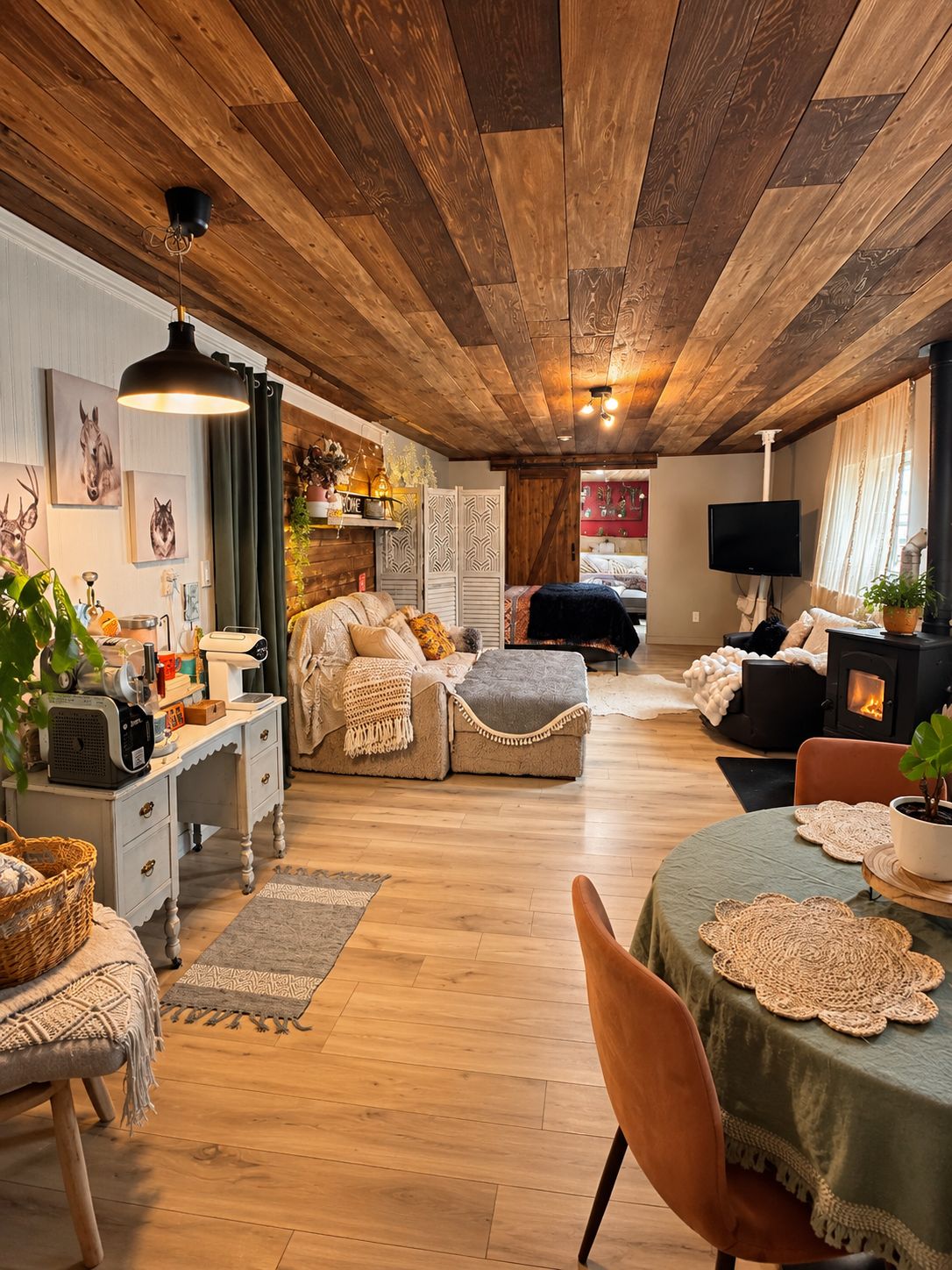 Un salon chaleureux avec une cheminée, un plafond en bois et un coin repas comprenant une table et des chaises.