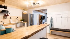 Una cocina moderna con encimera de madera, electrodomésticos de acero inoxidable y una zona de estar con un banco.