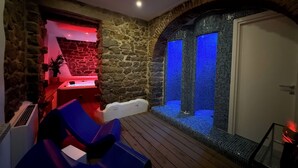 A spa area with stone walls, a seating area with blue chairs, and a blue-lit water feature. - EXORIA Luxury Rooms & Spa (Nuoro)