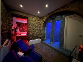 A spa area with stone walls, a seating area with blue chairs, and a blue-lit water feature.