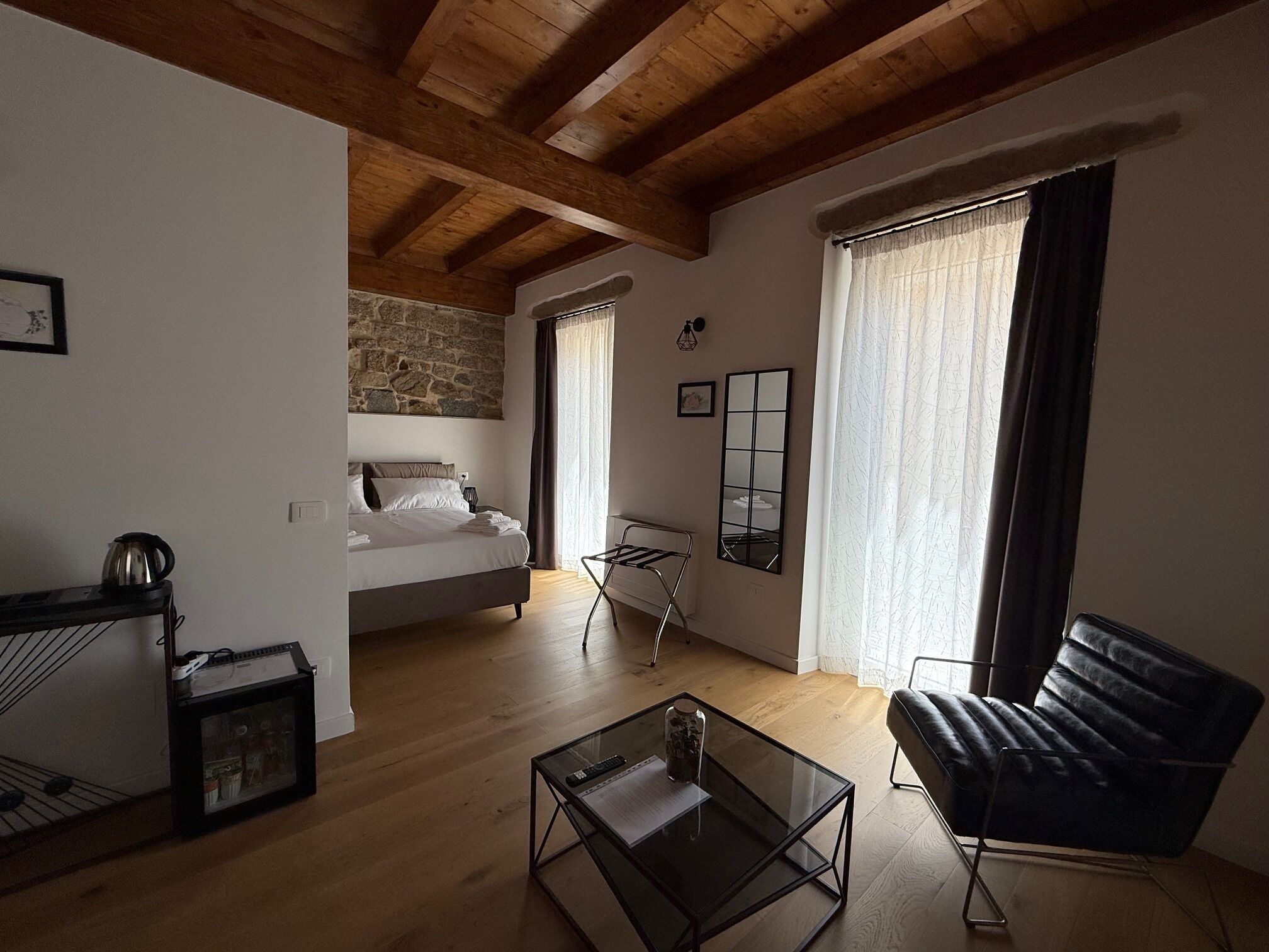 Ein modernes Wohnzimmer mit einem Bett, einem Glastisch, einer schwarzen Ledersofa und einer Steinwand.