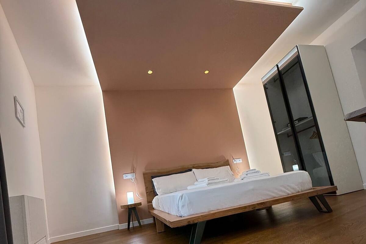 A modern bedroom with a wooden bed, a built-in wardrobe, and recessed ceiling lighting.